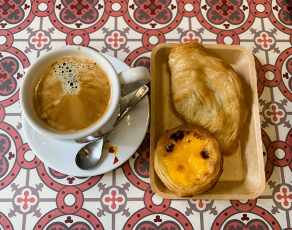 Coffee cup and two pastries on a table top decorated with Portuguese tile pattern