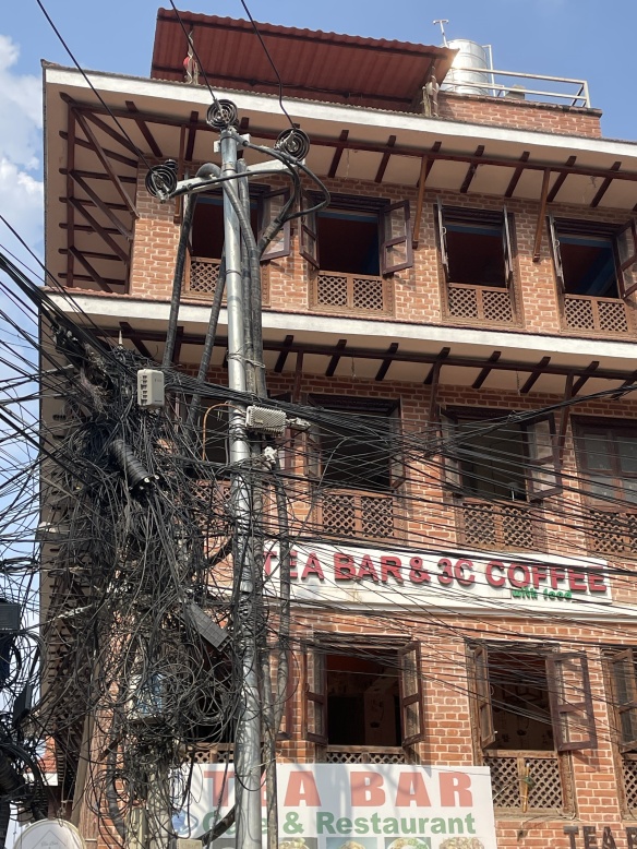 A rats' nest of electrical wires hanging on the electrical poles outside a tea and coffee shop