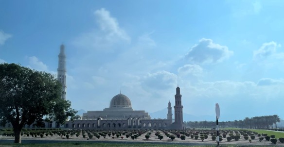 Outside view of mosque with large dome, tall minarets, and garden