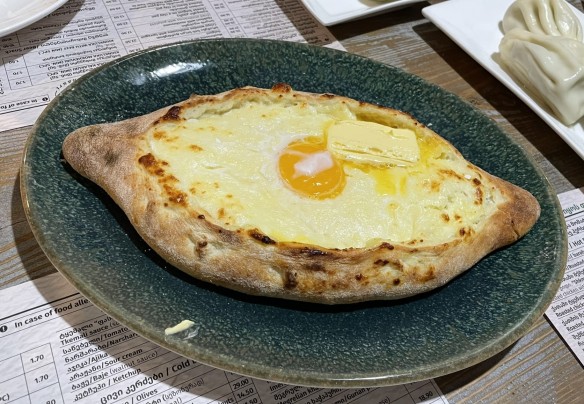 boat shaped bread stuffed with cheese and topped with an egg yolk and pat of butter