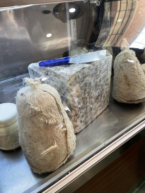 Display friedge filled with white cheeses wrapped in goat hair